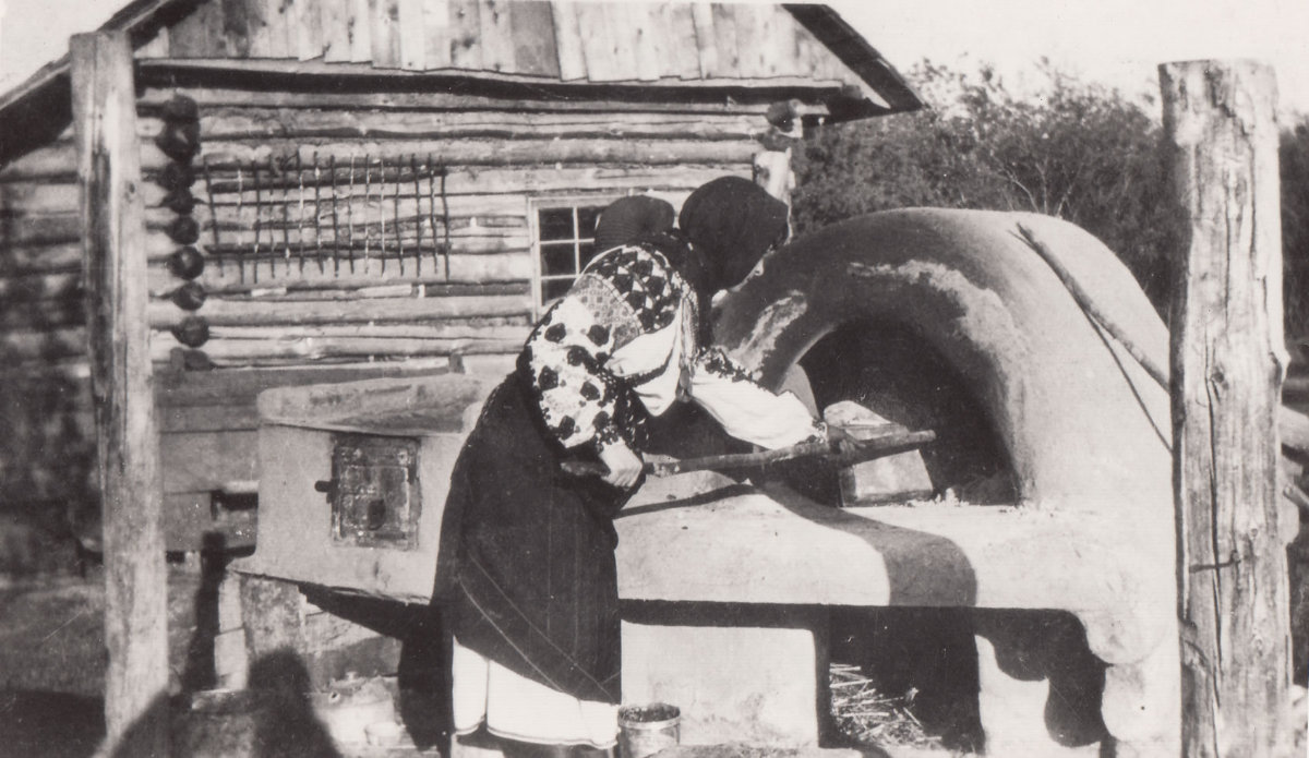 Palahna Nemirska-Miskiw, schoolteacher, at an open-air oven. Smoky Lake, Alberta, 1925